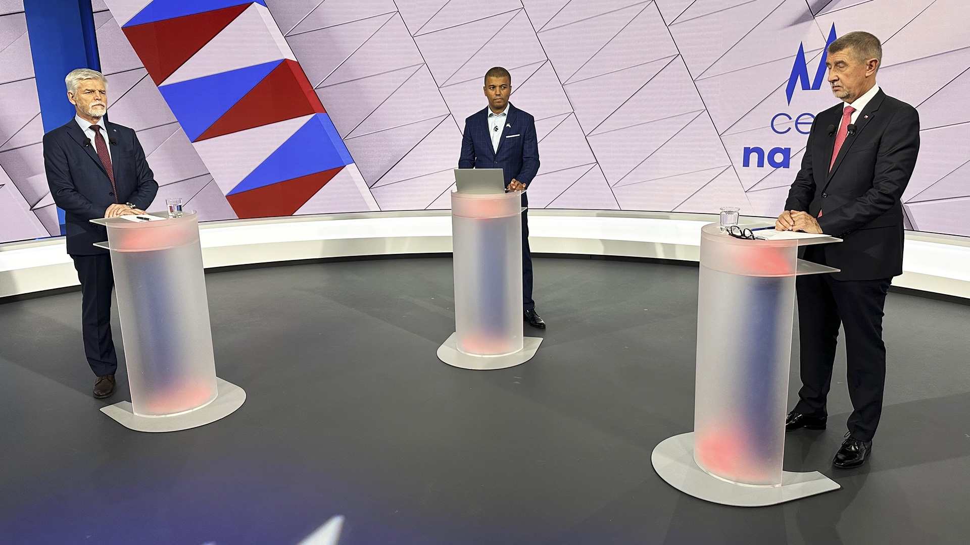 Petr Pavel and Andrej Babiš at lecterns in a television debate studio with a moderator between them