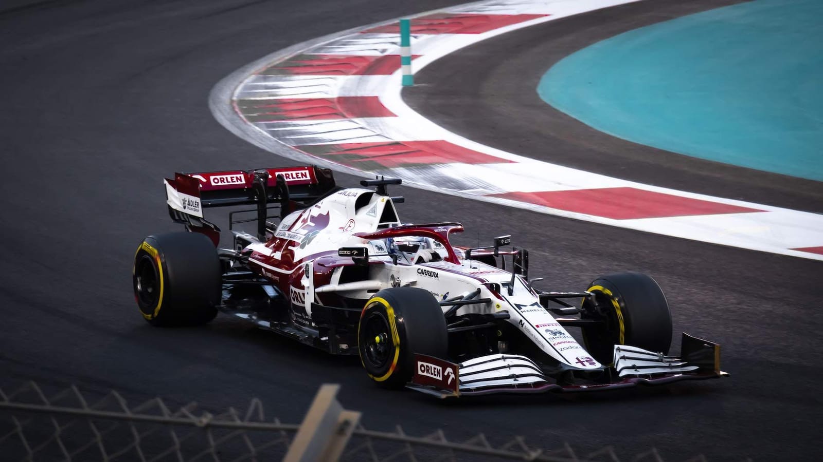 White and dark red Alfa Romeo Formula 1 car with Orlen branding cornering on a racetrack