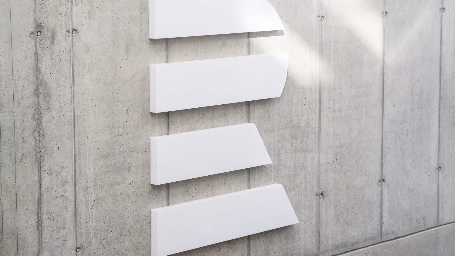 Four white sign panels on the concrete wall of Czech Radio's headquarters, angled so the lettering is unreadable