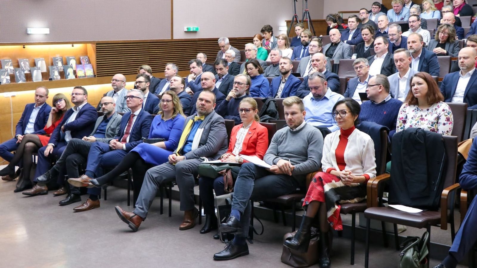 Audience of formally dressed people seated in a tiered lecture hall