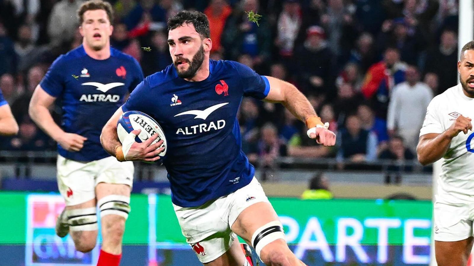 Rugby player in a blue France jersey with "ALTRAD" sponsor logo runs with the ball during a match