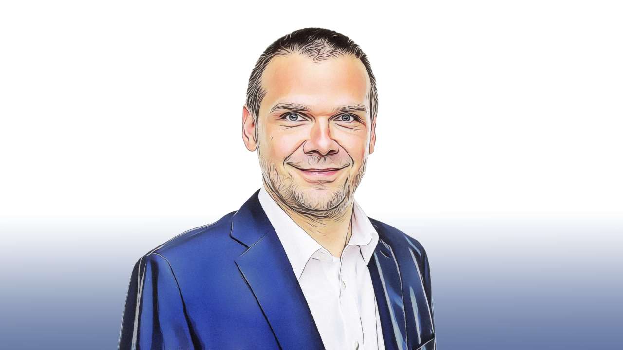 Stylised illustration of a smiling Martin Baxa with short hair and a beard, in a blue suit and white shirt on a white background