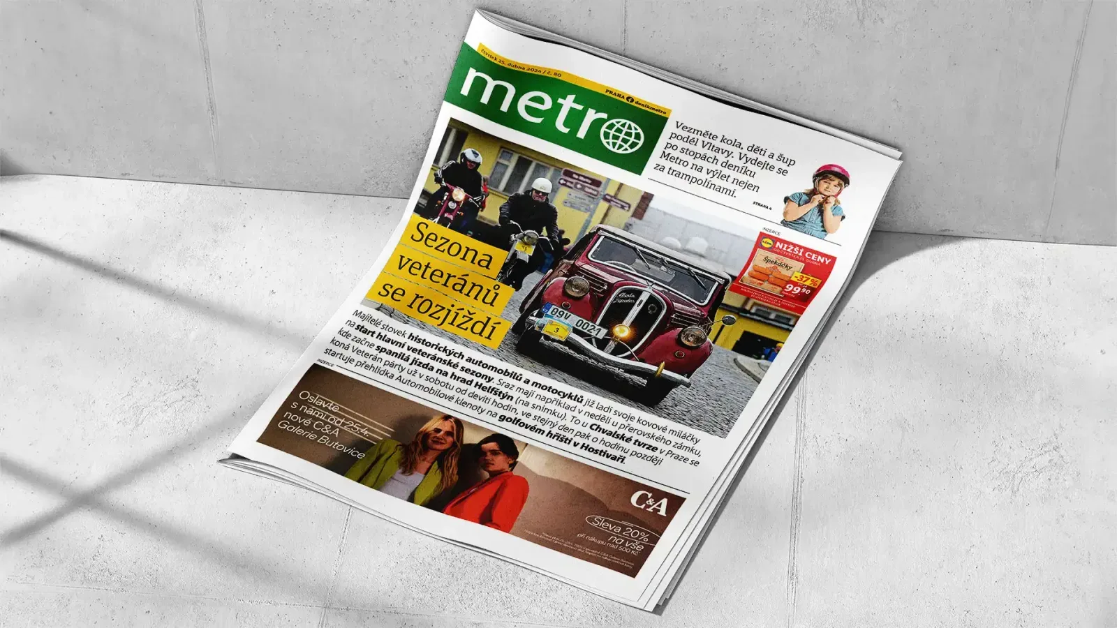 Illustrative photo of the free daily Metro on a grey surface, its front page featuring a vintage red car under the headline "Sezona veteránů se rozjíždí"