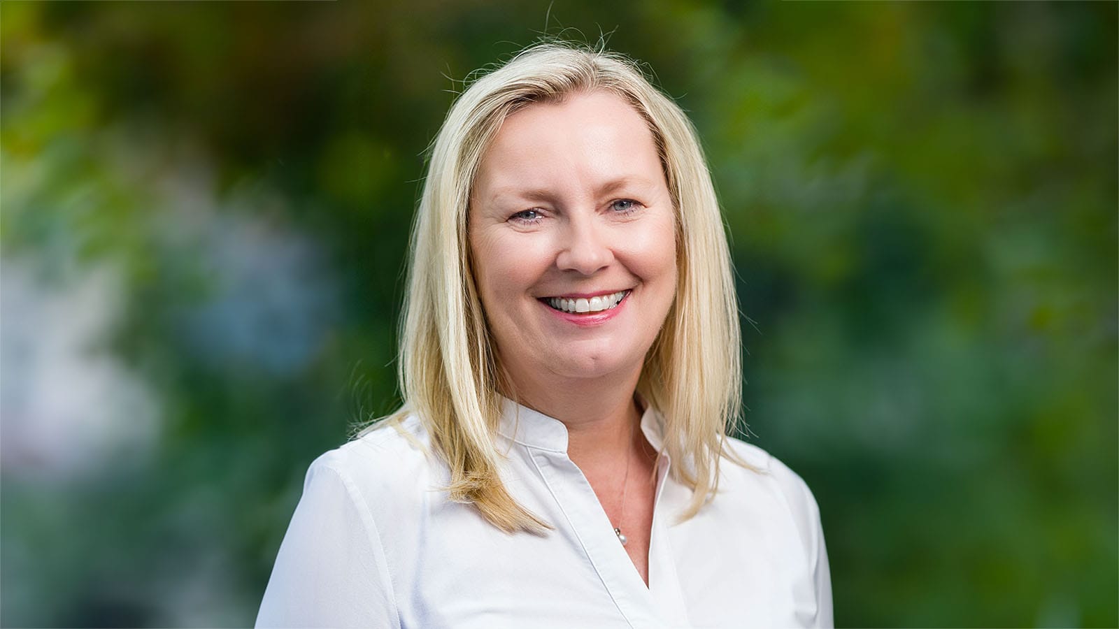 Klára Brachtlová of CME smiling in a white shirt against a blurred green background