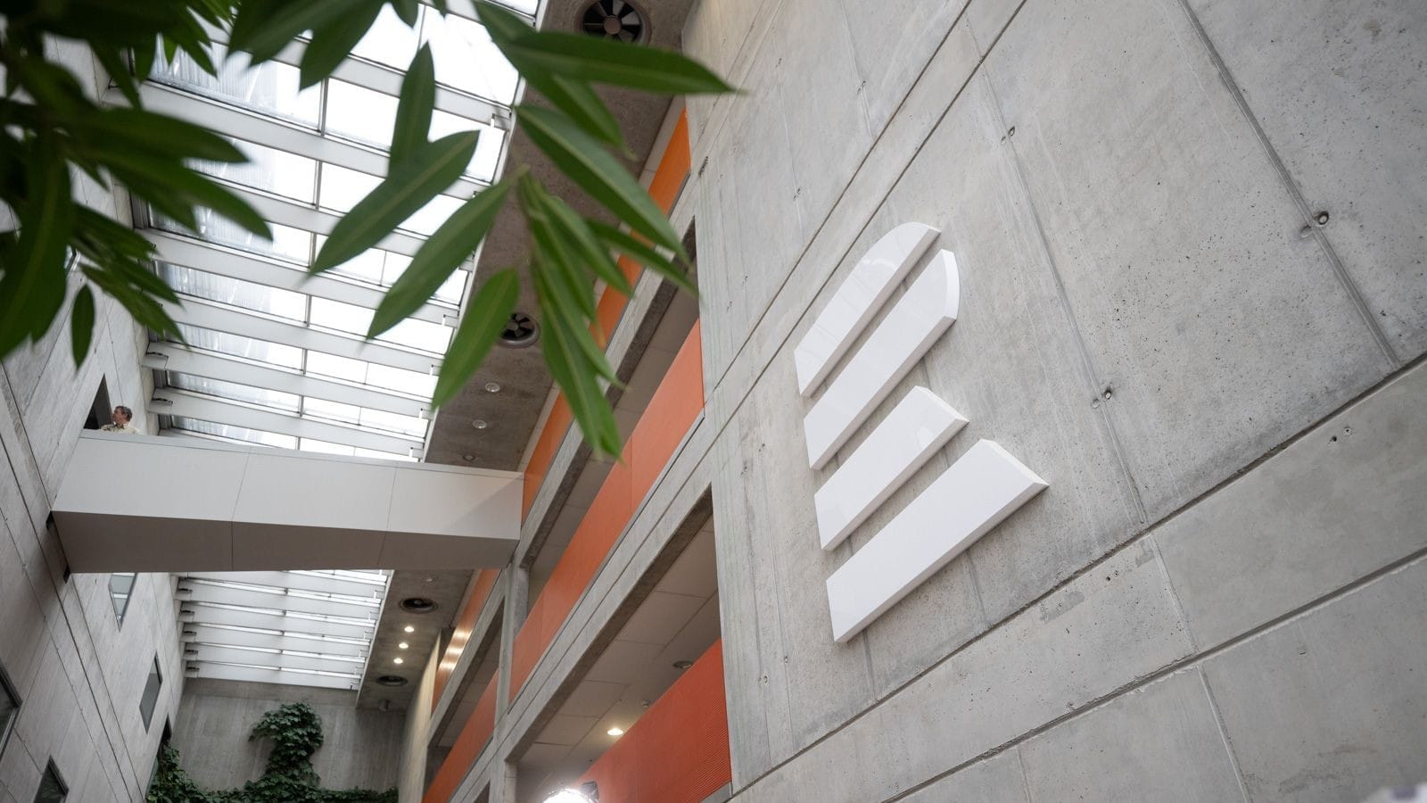 White Czech Radio logo on a concrete wall in the glass-roofed atrium of the Czech Radio headquarters, seen from below