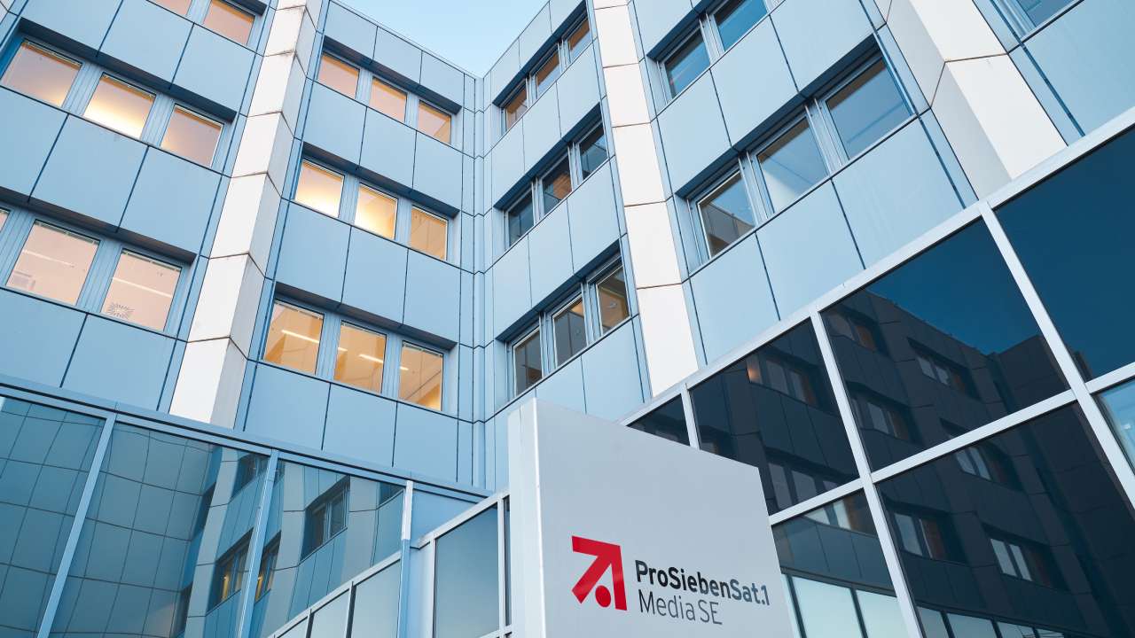 Modern glass office building seen from below with a sign reading ProSiebenSat.1 Media SE