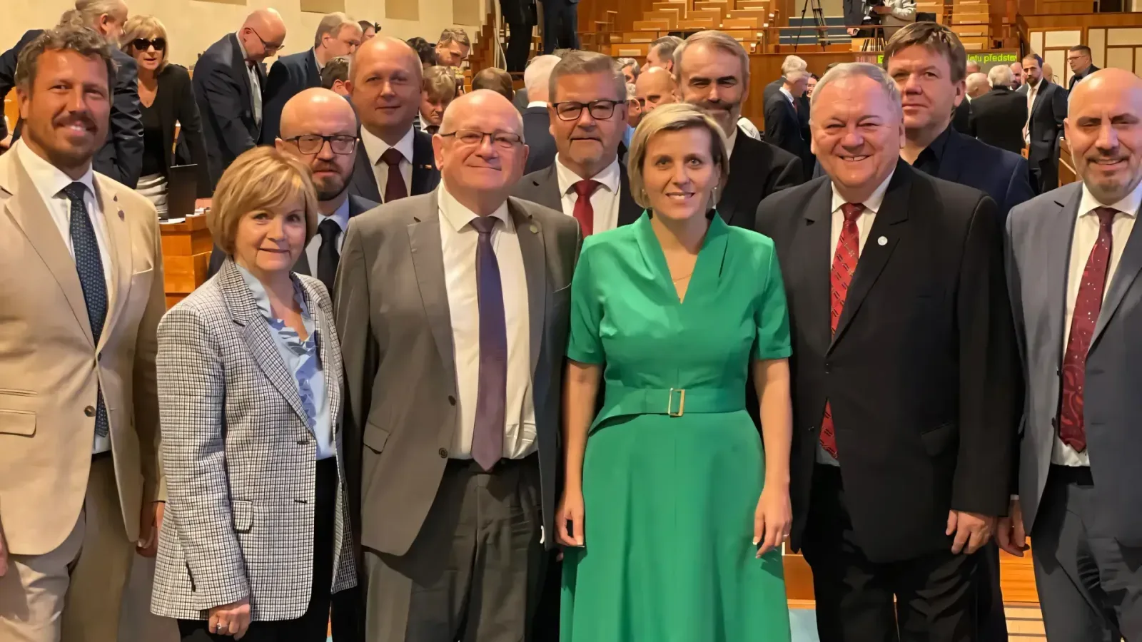 Senator Jana Mračková Vildumetzová in a green dress standing with her fellow politicians in the parliamentary chamber