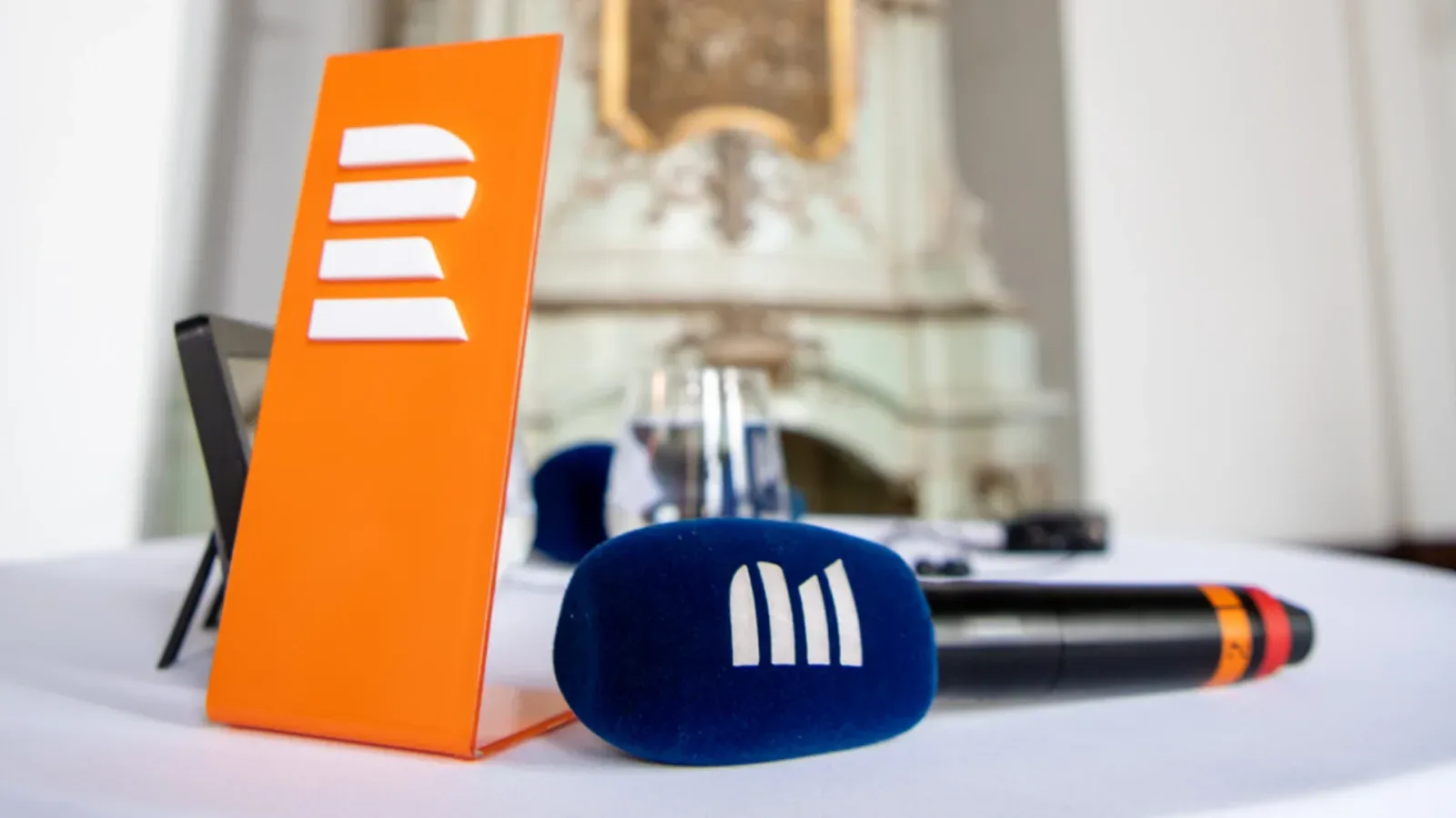 Orange Czech Radio logo stand and a microphone with blue windscreen on a white table