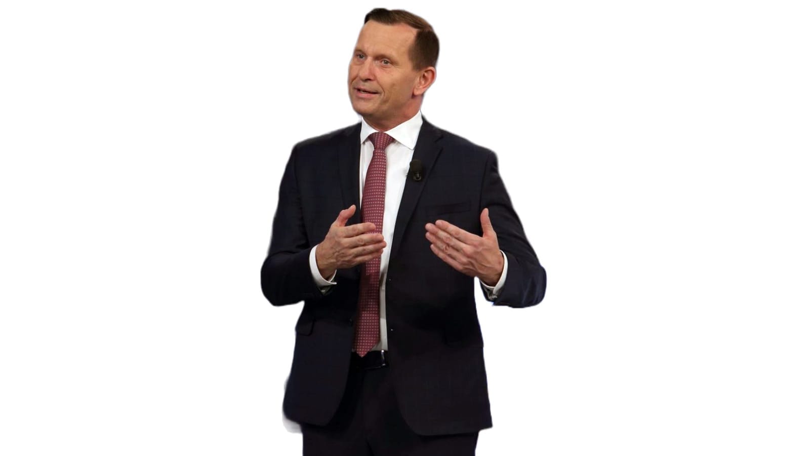 Jaromír Soukup in a dark suit and red patterned tie gesturing with both hands while speaking against a white background
