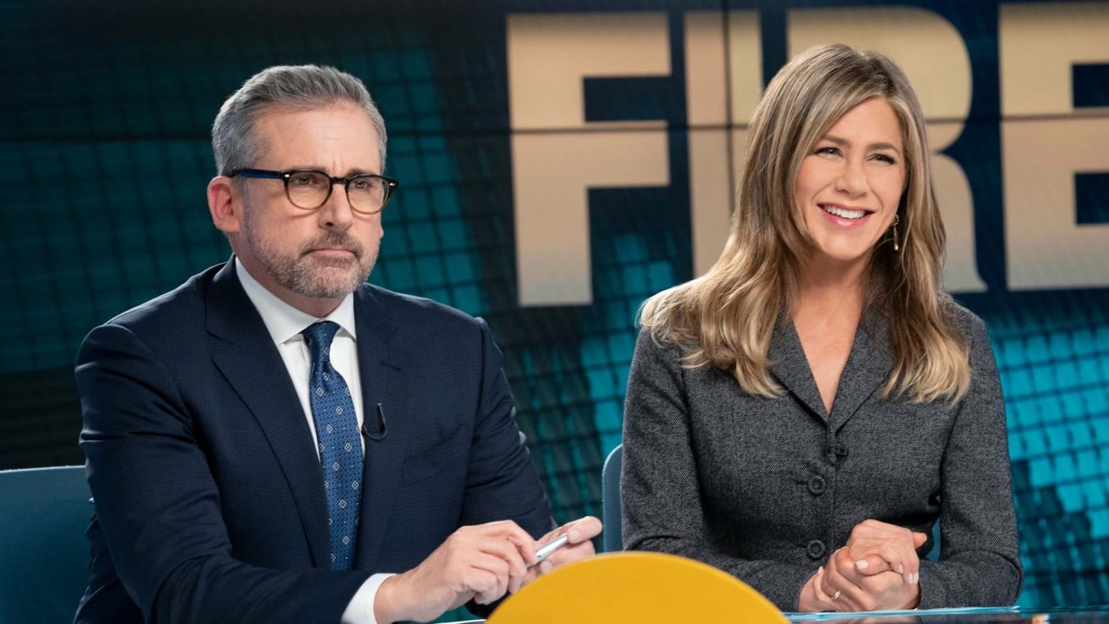 Steve Carell and Jennifer Aniston at a news desk in a scene from the TV series The Morning Show
