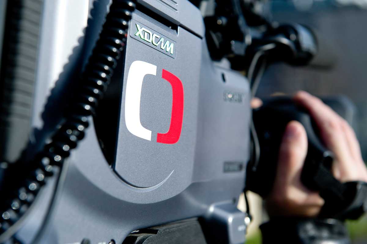 Close-up of a Sony XDCAM television camera bearing the red and white Czech Television logo, with a hand on the grip