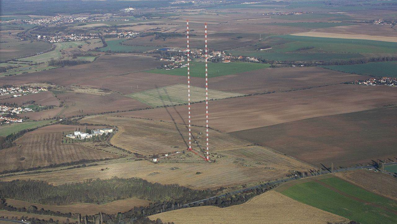 Aerial view of the Liblice transmitter near Český Brod, its two red-and-white masts rising above flat farmland and villages
